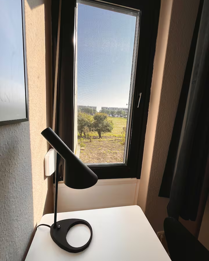 Schwarze Schreibtischlampe am Fenster der ZweiteLiebe mit Blick ins Grüne.
