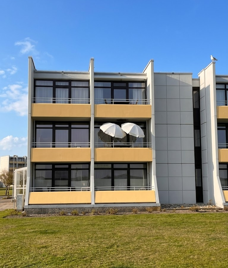Dreigeschossiges Appartementhaus der Meerzeitliebe mit gelben Balkonbrüstungen und senkrechten Fassadenelementen.