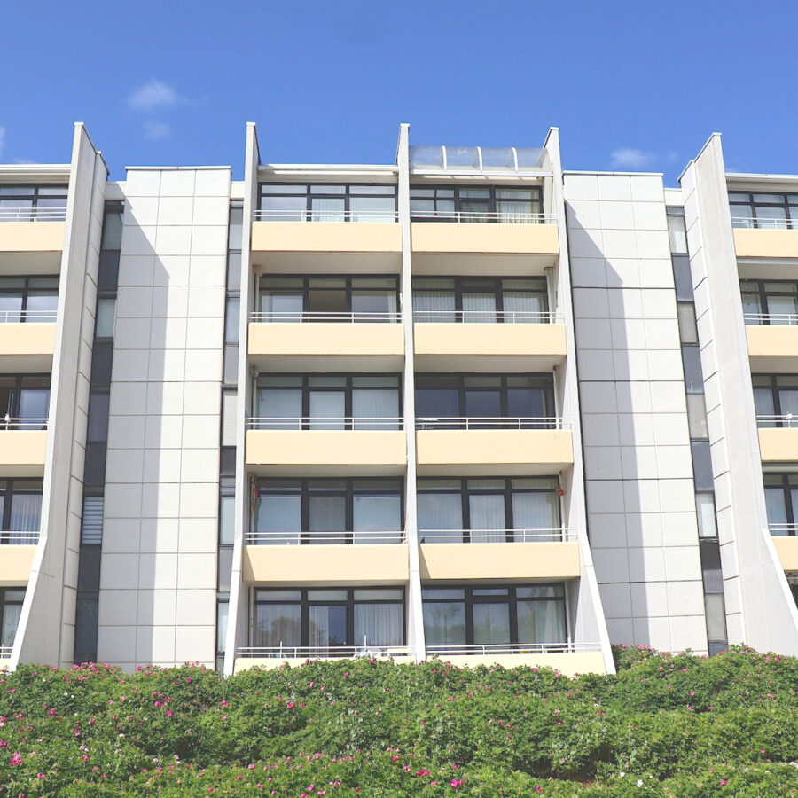 Fünfgeschossiges Appartementhaus der Arne-Jacobsen-Siedlung mit hellen Fassaden und gelben Balkonbrüstungen.